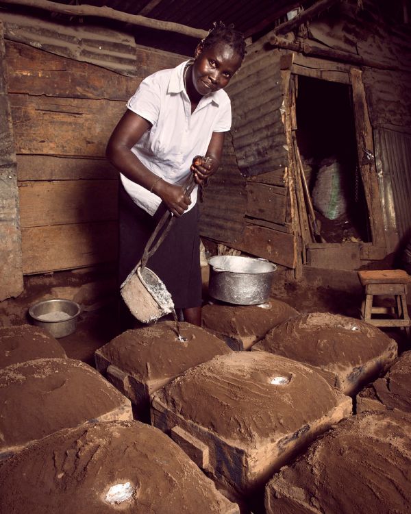 Betty pours molten metal into dirt-covered molds to make cooking pots